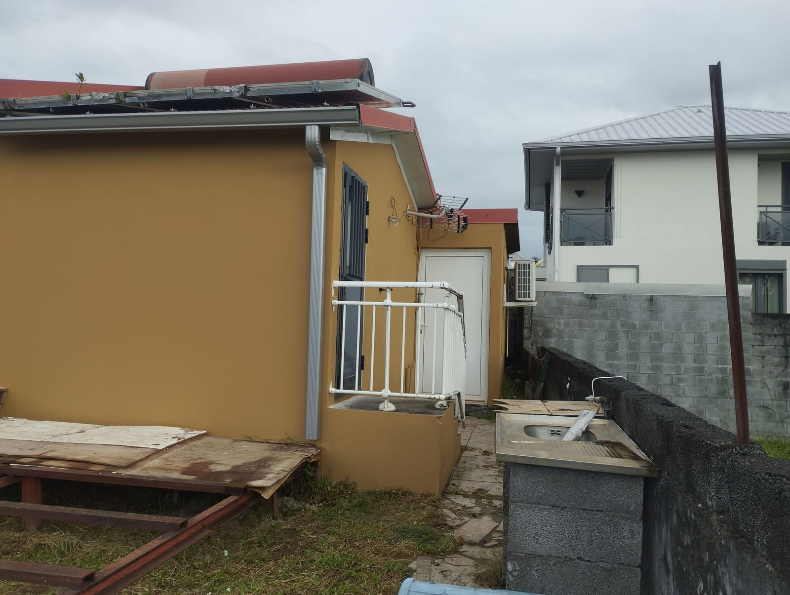 Pignon arrière d’une maison en finition ocre avec garde-corps blanc et descente en zinc
