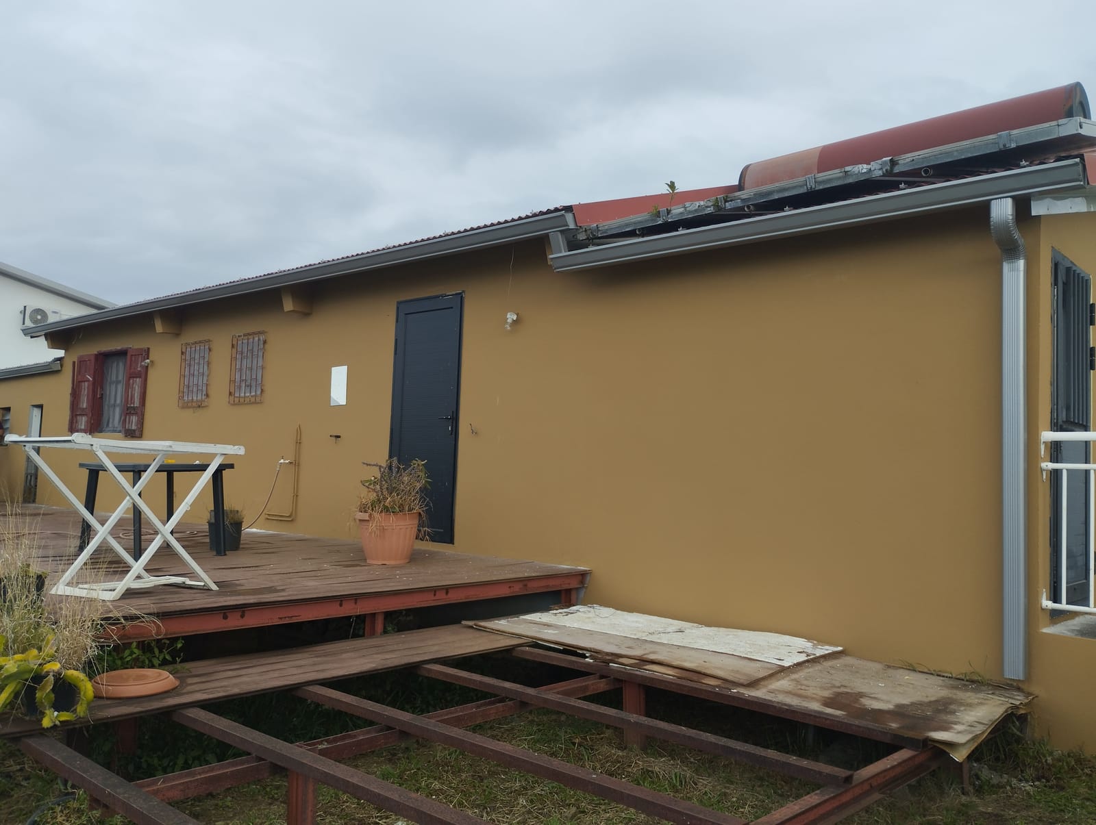 Façade côté terrasse en bois repeinte en ocre, store banne et menuiseries anthracite